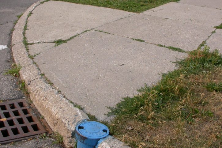  a sidewalk with no curb cut, and a grate in the center