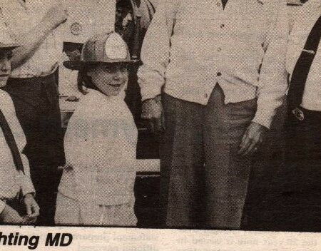 An old newspaper clipping with Dom as a child wearing a fireman's helmet.